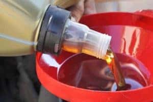 Mechanic pouring oil in car