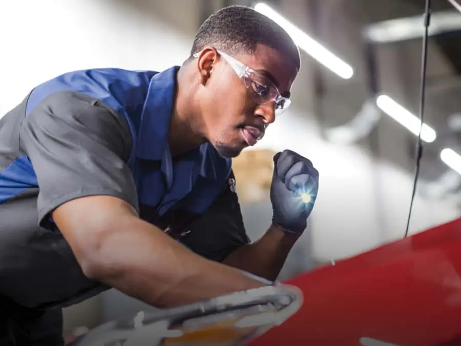 Service Tech is inspecting vehicle under the hood.