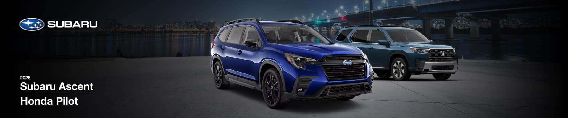A blue 2026 Subaru Ascent and a green Honda Pilot parked in front of a city waterfront at night.