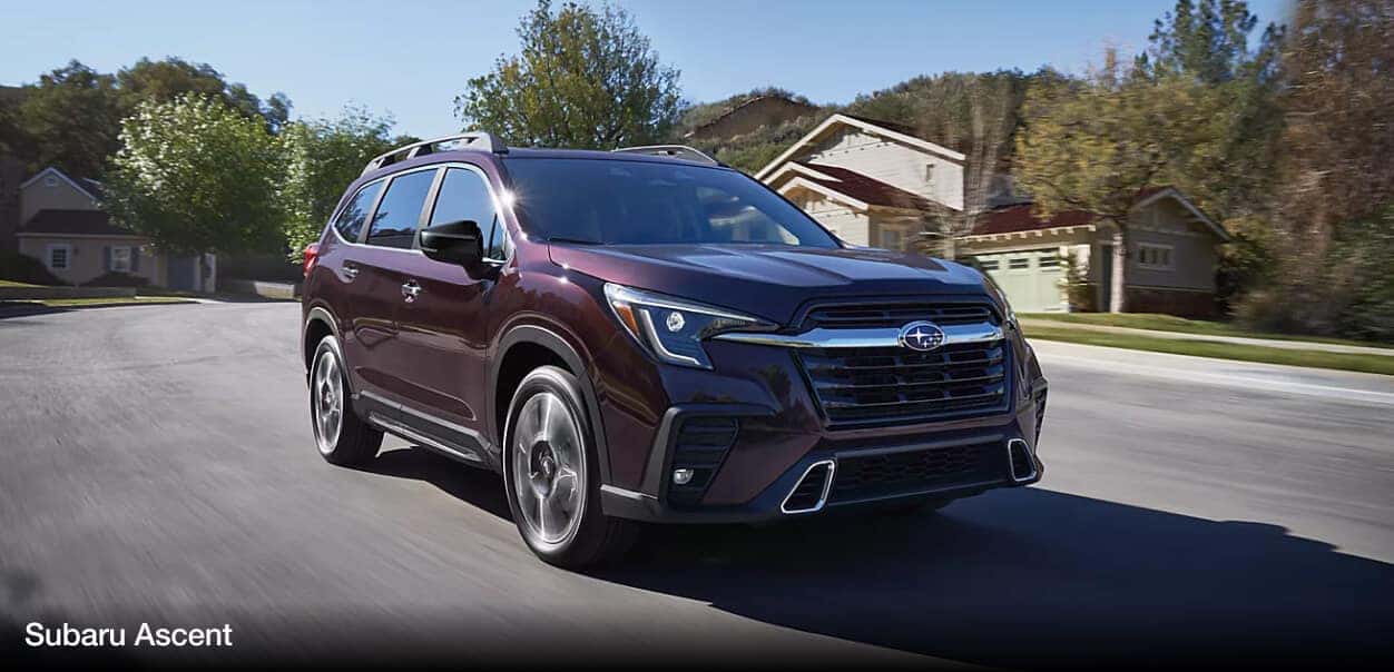 An auburn Subaru Ascent drives down a suburban street.