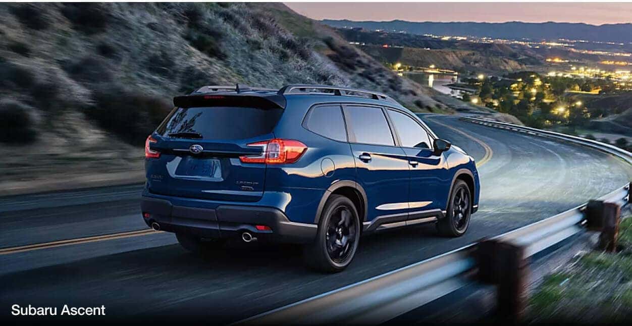 A blue Subaru Ascent drives down a windy cliffside road.