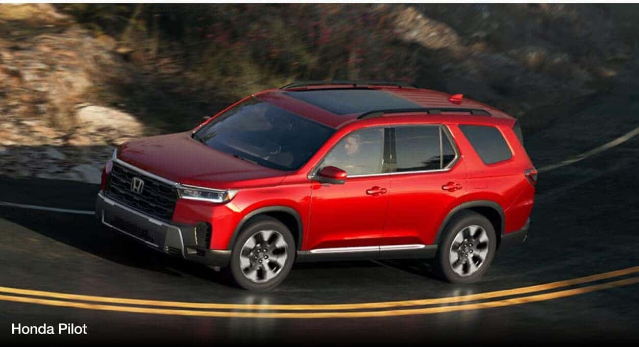 A red Honda Pilot corners on a windy road.