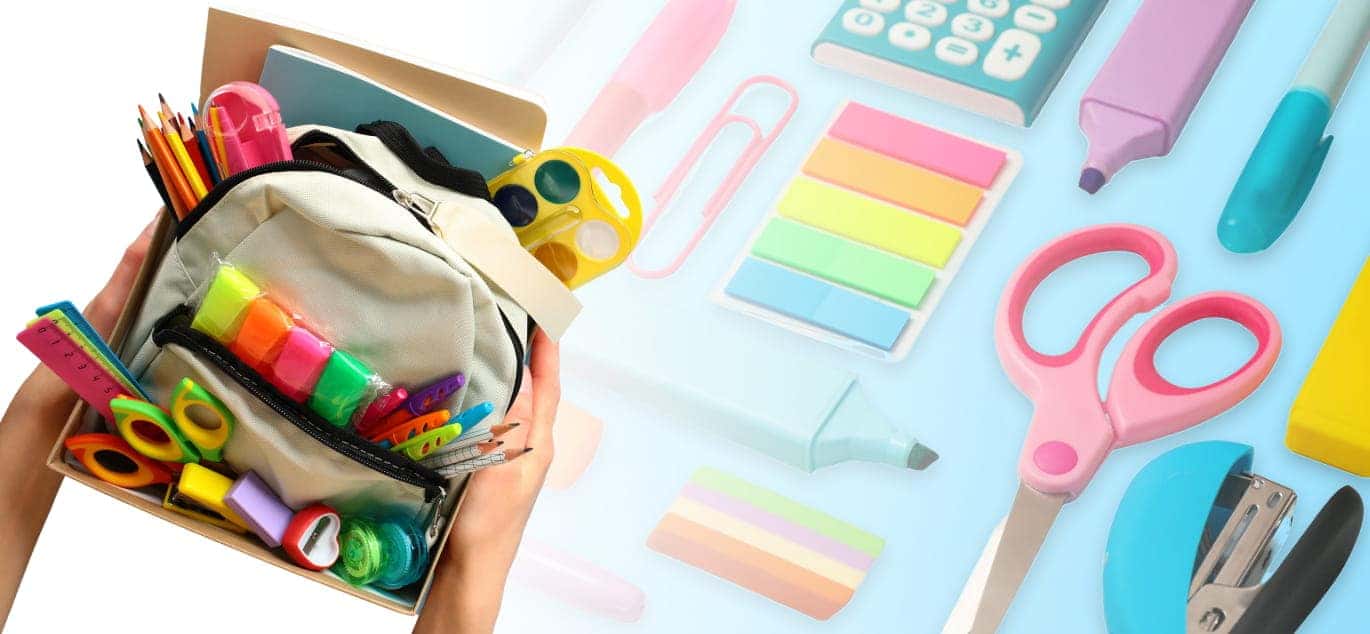 Hands holding a backpack filled with colorful school supplies, surrounded by pencils, scissors, and other classroom essentials.