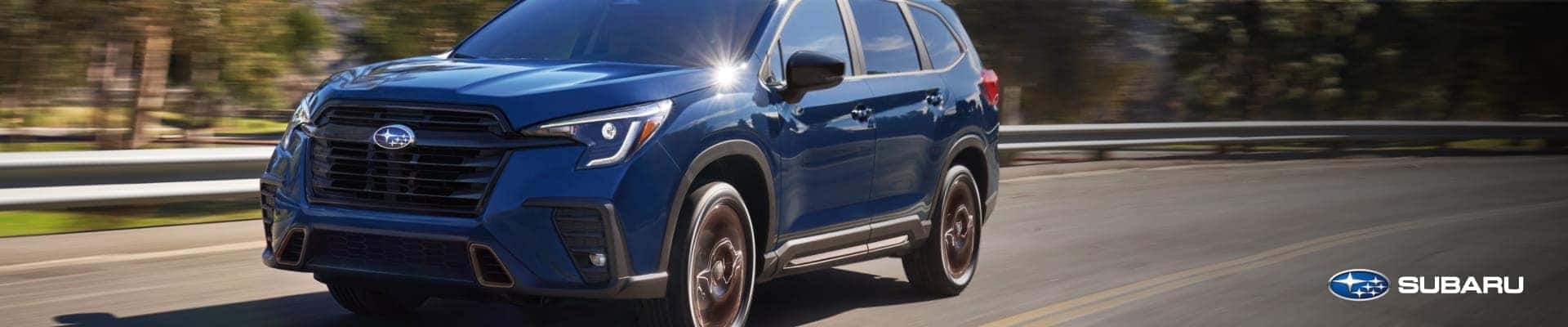 Blue Subaru Ascent driving on a road, shown from a front three-quarter angle.