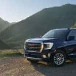 GMC Yukon driving near a mountain on a dirt road