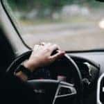 left hand with watch and wedding ring on the steering wheel of a GMC vehicle