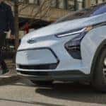 2022 Chevrolet Bolt EV exterior front detail of vehicle parked curbside with male talent walking next to vehicle