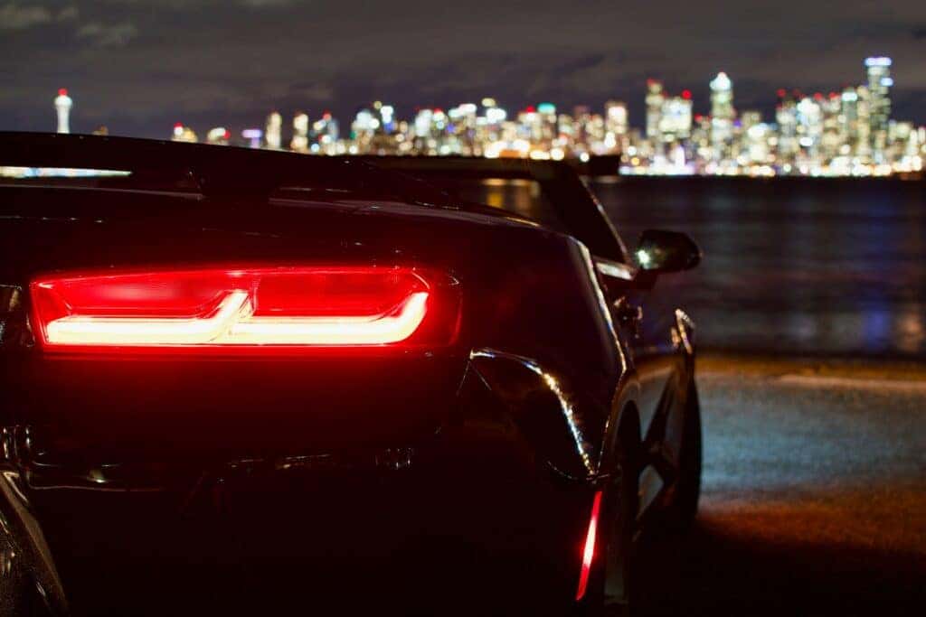 A Black Chevy Car at night looking out on a city skyline
