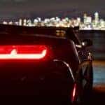 A Black Chevy Car at night looking out on a city skyline
