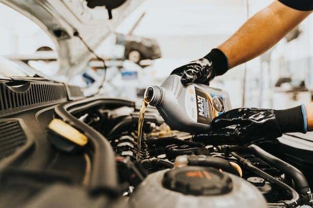 mechanic pouring engine oil into a car