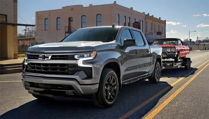 Gray 2026 Chevrolet Silverado towing a classic car