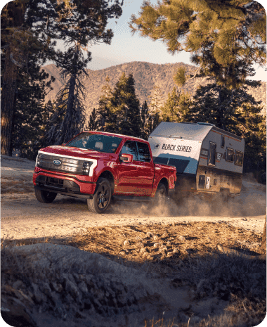 Truck pulling a trailer up a dirt road.