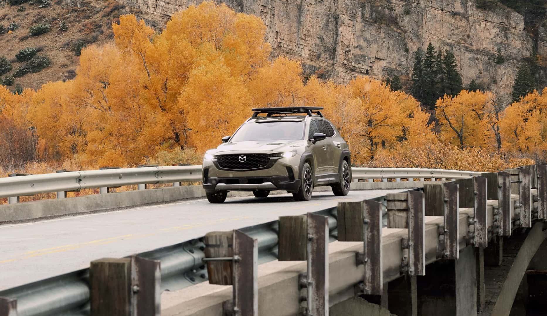 Mazda CX-50 driving across a bridge in the autumn