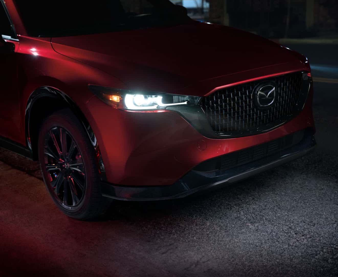 Close up on front of a Mazda CX-5 with its headlights on at night