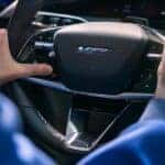 Image of a person driving an Optiq-V, and pressing the V-Button