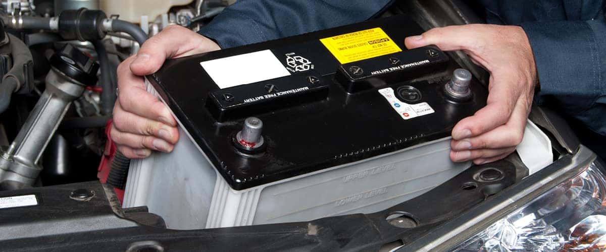 Nissan Technician installing a genuine Nissan car battery into a Nissan Altima