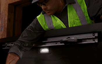 Worker in a safety vest using LED bed lighting in the Frontier truck bed