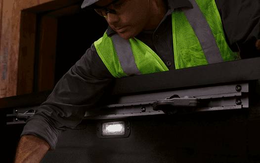 Worker in a safety vest using LED bed lighting in the Frontier truck bed