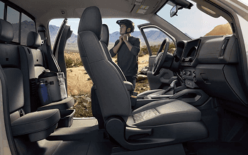 Side view of the Frontier front seats with driver standing outside in the desert
