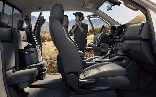 Side view of the Frontier front seats with driver standing outside in the desert