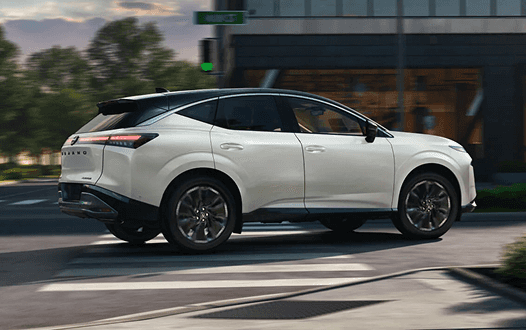 Side view of a white Murano driving through a city intersection