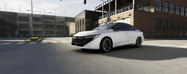 Front three-quarter view of a white Sentra driving through a downtown street