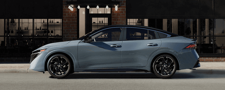 Side profile of a gray-blue Sentra parked outside a brick restaurant