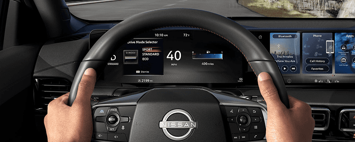 Driver's hands on the Sentra steering wheel with Drive Mode Selector showing on the cluster