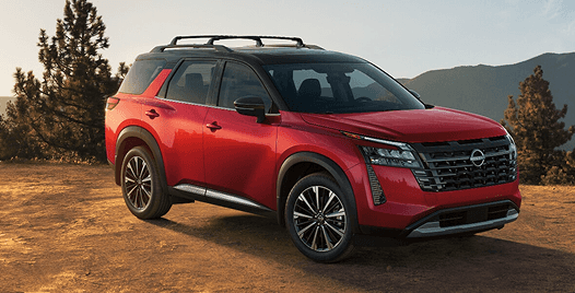 Red Pathfinder parked on a dirt clearing with mountains in the background