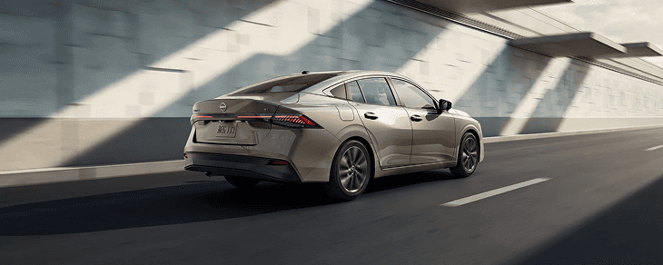 Rear three-quarter view of a champagne Sentra driving through a tunnel