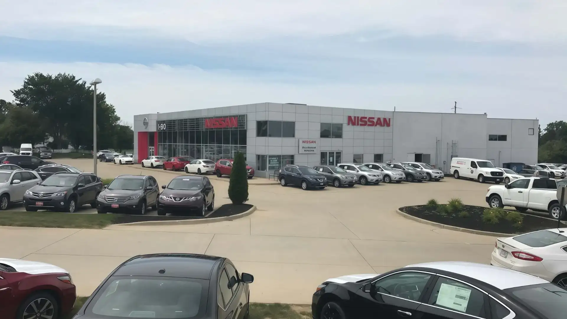 I-90 Nissan dealership exterior — 5013 Detroit Rd, Sheffield Village, Ohio, showing the showroom, NISSAN signage, and inventory lot