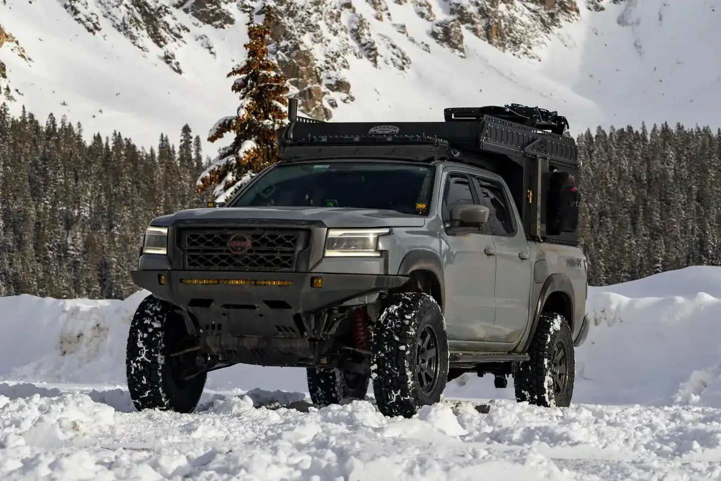 Nissan Frontier 4WD parked in deep snow below a snow-covered mountain ridge, illustrating the drivetrain's cold-weather traction