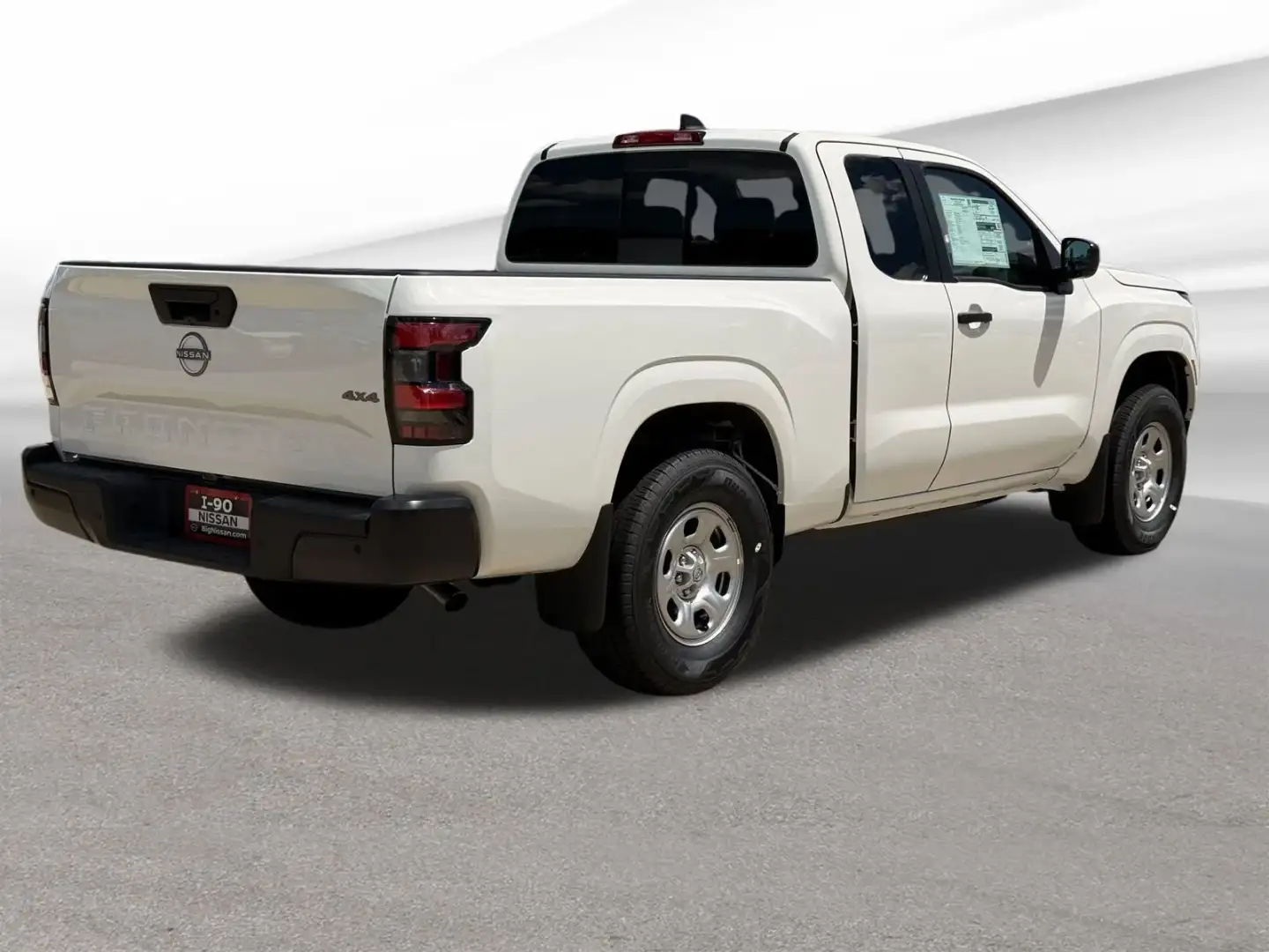 Rear three-quarter passenger side of a 2026 Nissan Frontier with the I-90 Nissan license plate frame