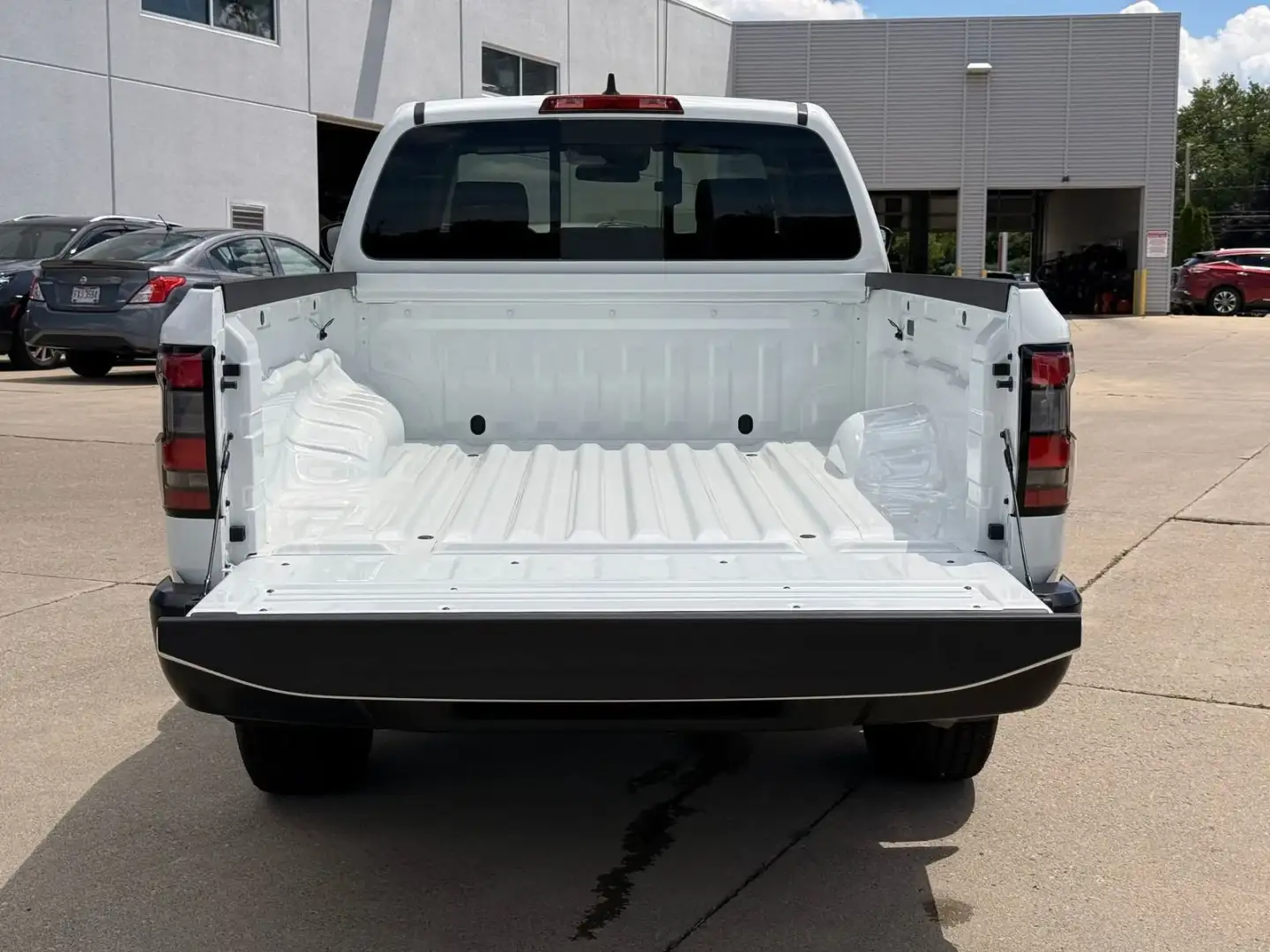 Tailgate down showing the Frontier bed with the I-90 Nissan dealership building behind it