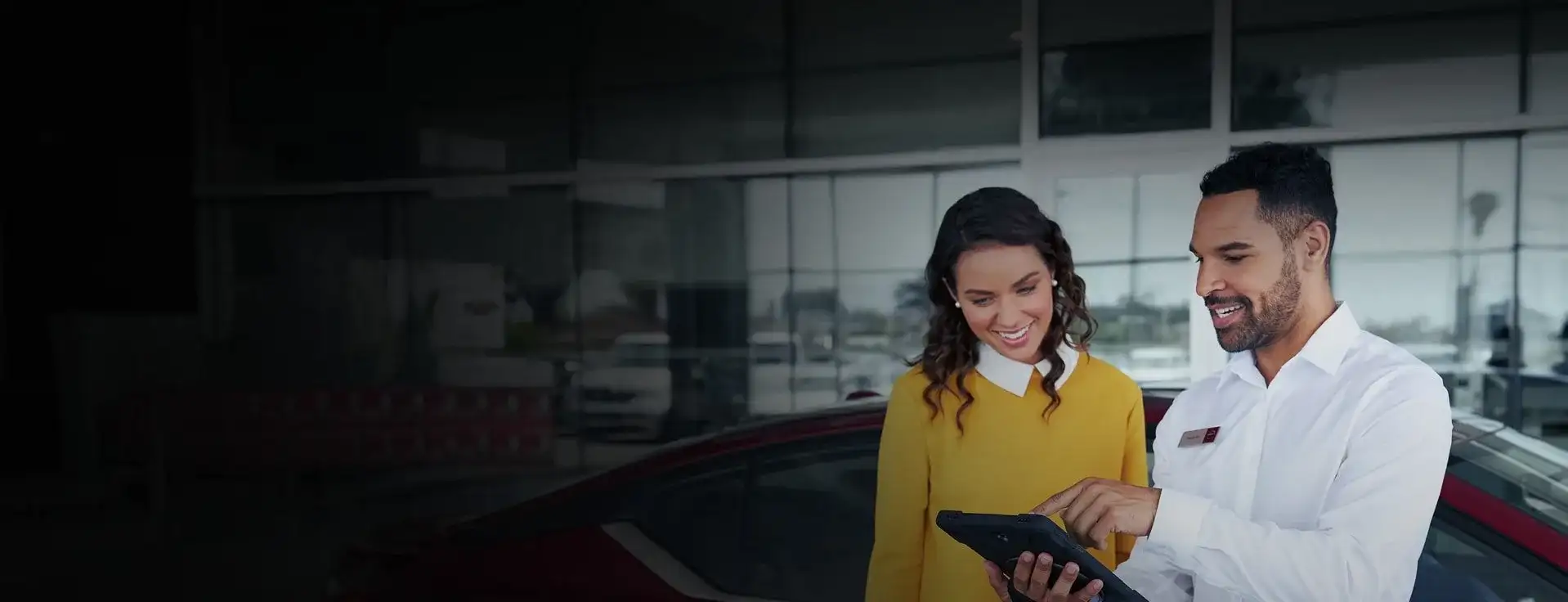 An I-90 Nissan finance manager reviewing pre-approval on a tablet with a customer in the showroom — Lorain County financing in Sheffield Village, OH