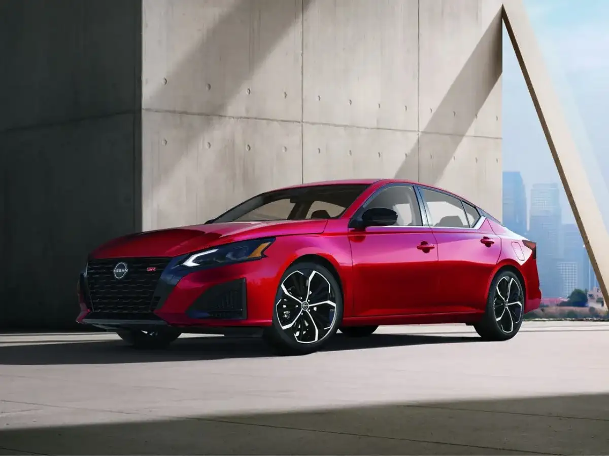 Red Nissan Altima SR sedan driving through a city at night, highlighting its sporty styling and performance, available at I-90 Nissan near Medina, OH.
