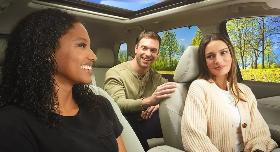Three people riding in a Nissan cabin on a spring day, the driver and front passenger turning to the passenger in the back