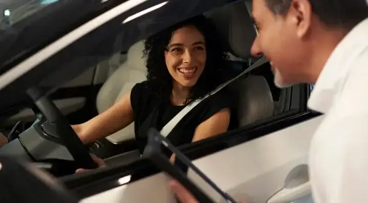 A customer in the driver's seat of a certified pre-owned Nissan talking with a member of our team at I-90 Nissan