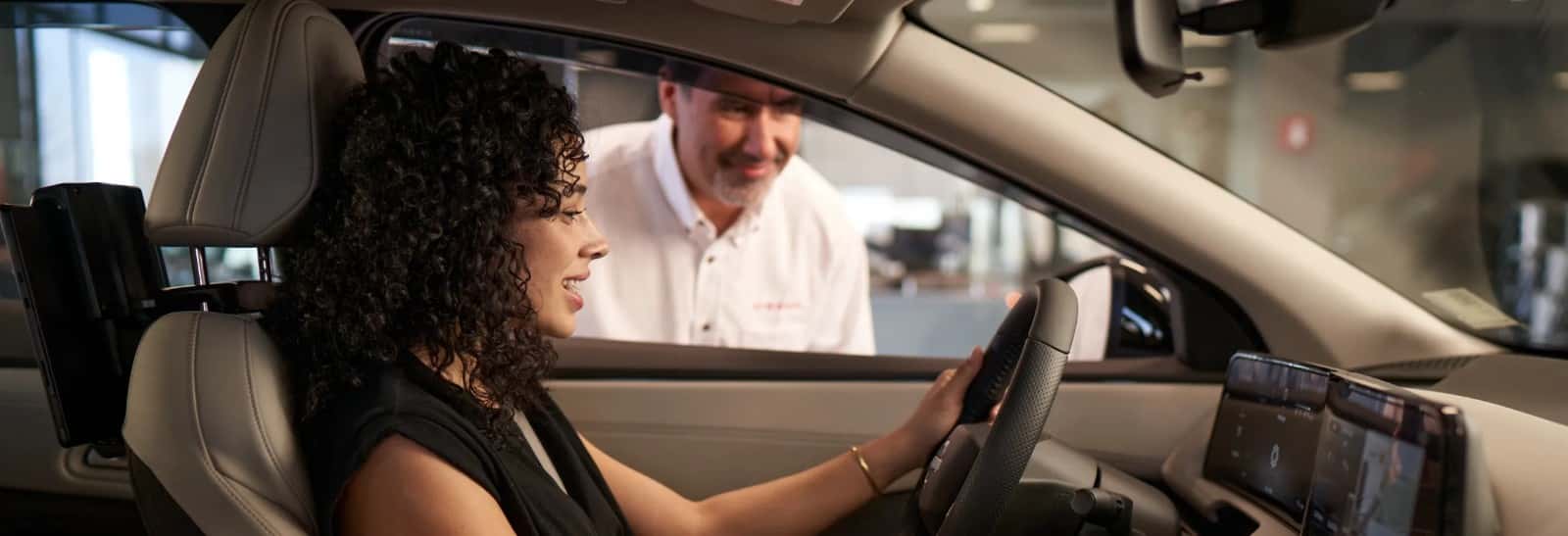 A Nissan advisor talking to a driver through the open window of a car on the service drive