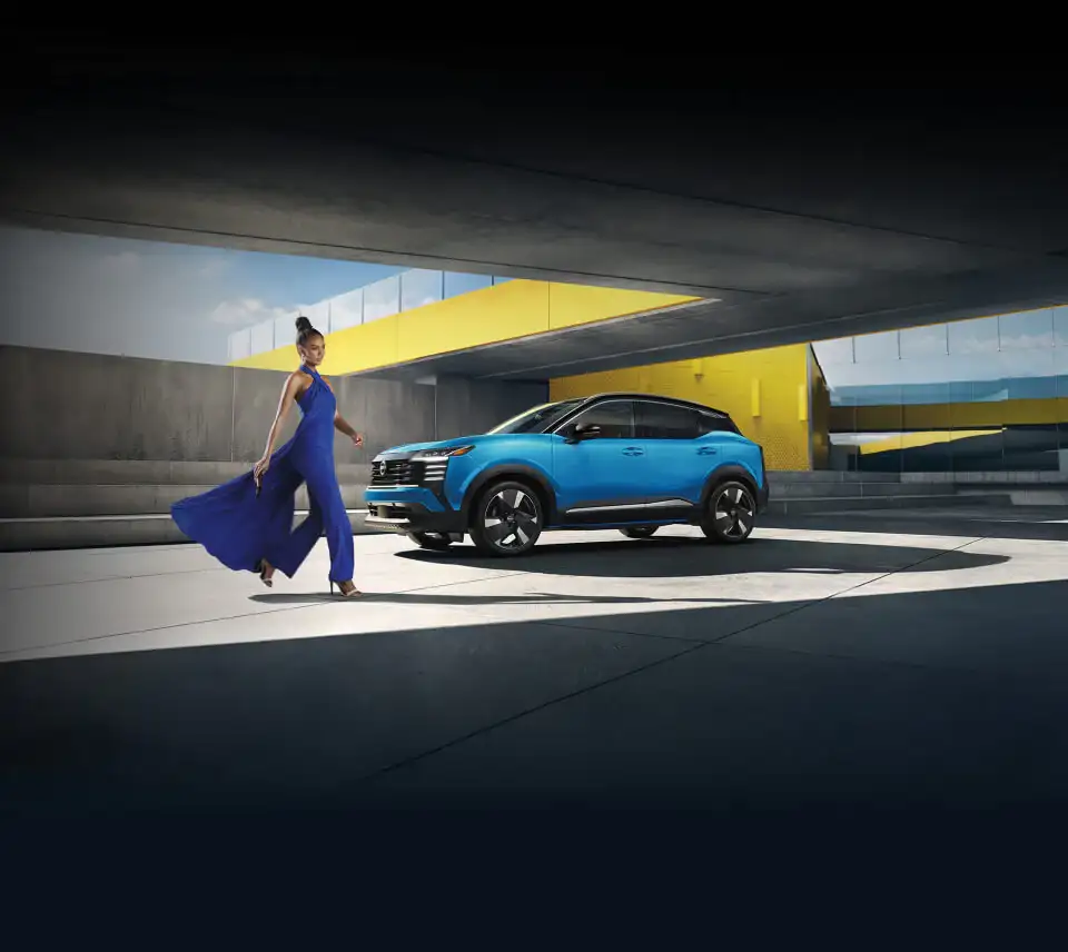 Nissan Kicks in blue, side profile, parked in a concrete and yellow architectural setting