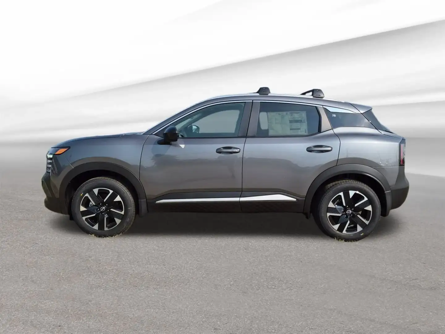Nissan Kicks in gunmetal gray, full side profile showing the roof rails and wheels