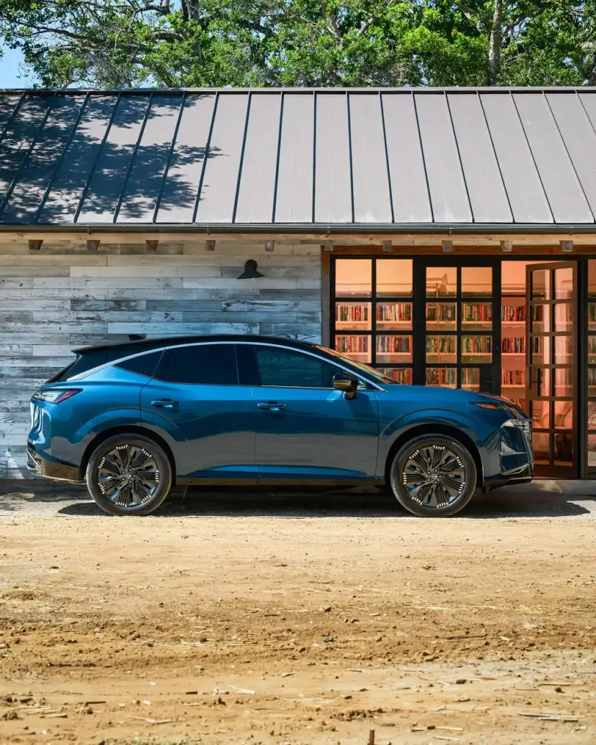 Nissan Murano in blue, side profile, parked in front of a modern cabin