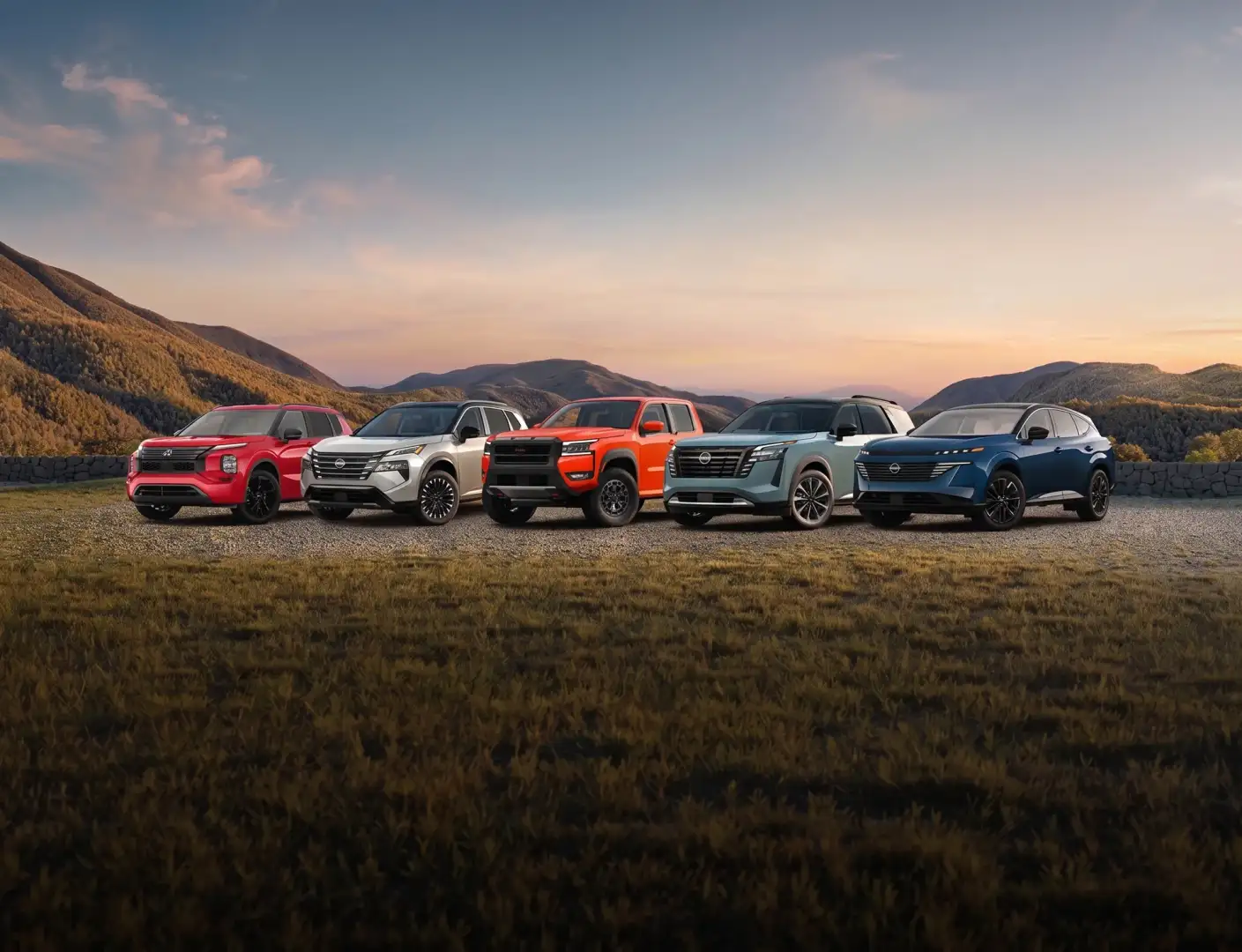 Five vehicles lined up on a gravel overlook at sunset: four Nissans, including a pickup, beside a red Mitsubishi Outlander