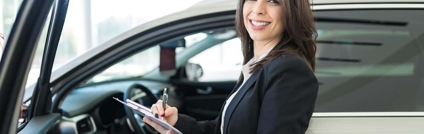 Woman Signing Papers in Front of Car