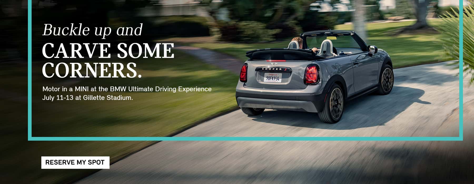 MINI convertible cruising down road.