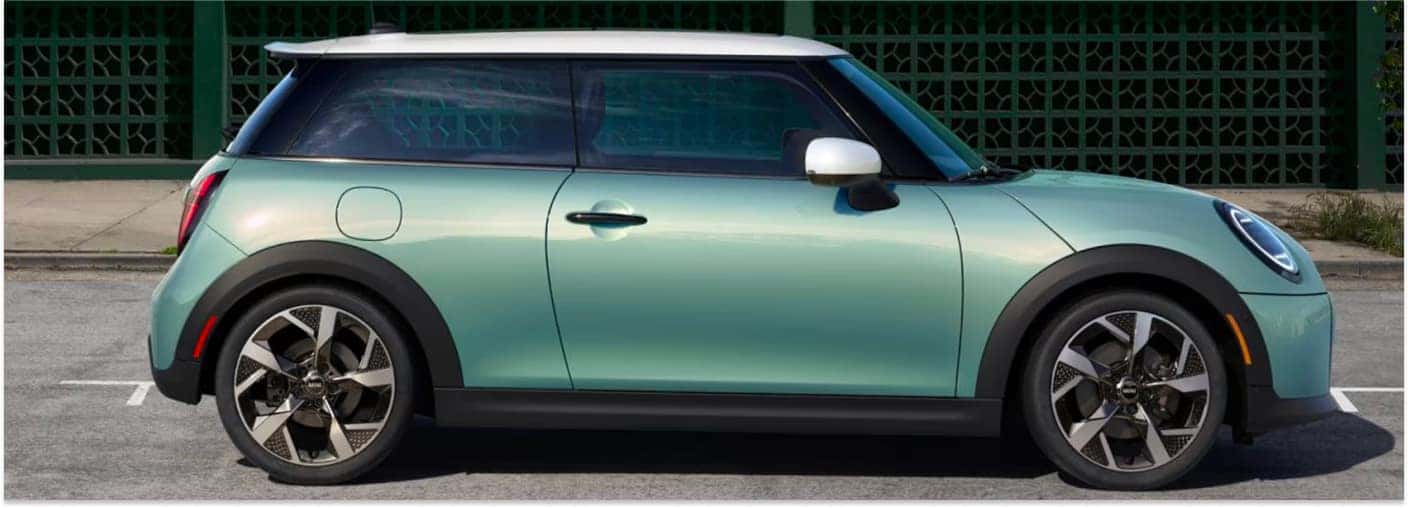 Side profile view of a mint green 2027 MINI Cooper 2 Door with a white roof and two-tone wheels.