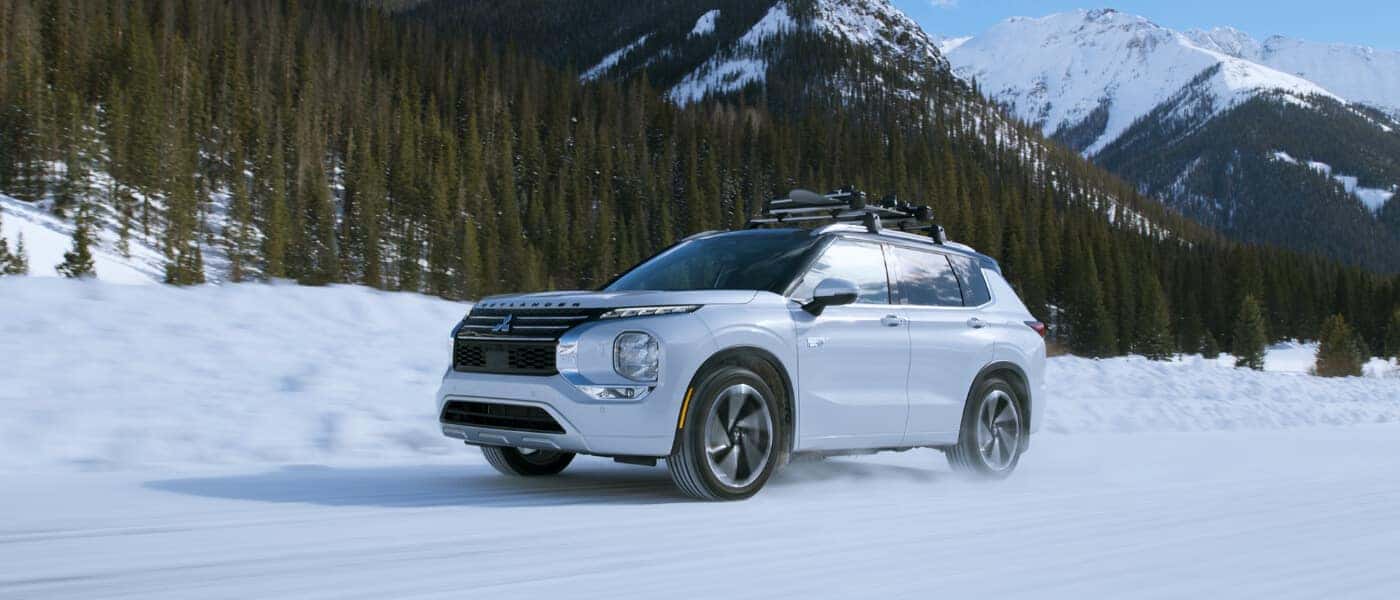 2025Mitsubishi-OutlanderPHEV-ExteriorDrivingInSnowSideView