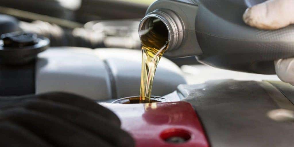hand pouring oil into car