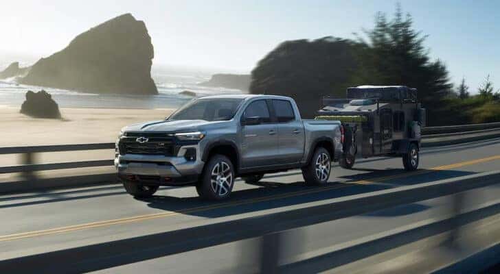 A silver 2024 Chevy Colorado Z71 is shown driving to a Chevy dealer.