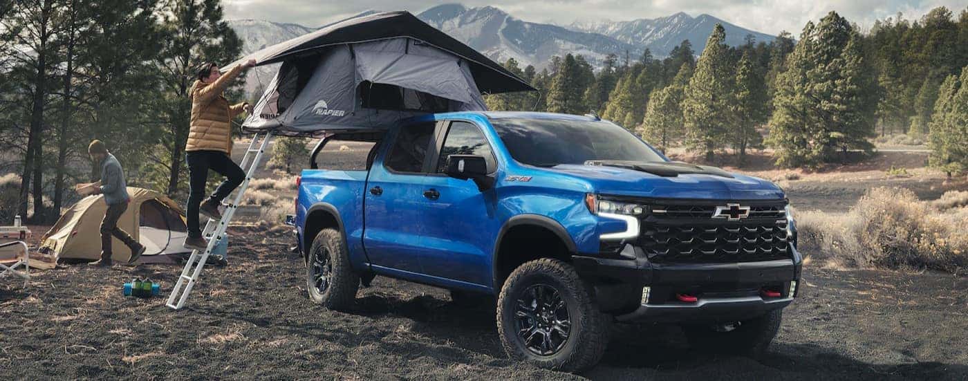 A blue 2025 Chevy Silverado 1500 ZR2 is shown parked on a campsite.